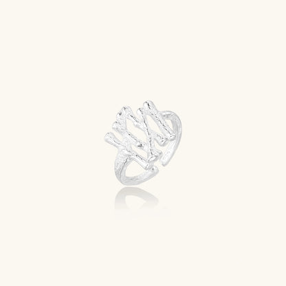 Sculptural sterling silver ring with organic branch design and textured surfaces on cream background
