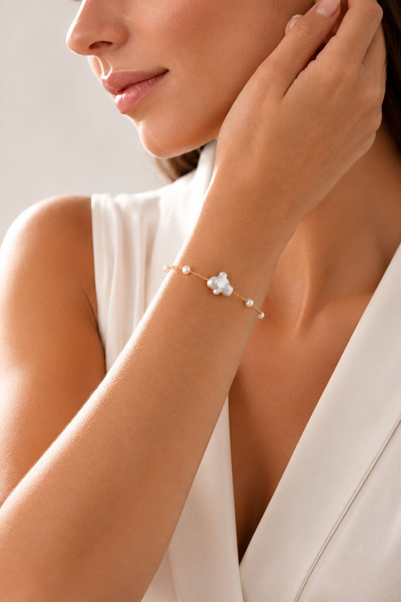 Elegant woman wearing a delicate gold bracelet with white pearls in a soft luxury jewelry setting