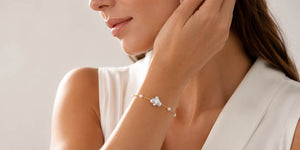 Elegant woman wearing a delicate gold bracelet with white pearls in a soft luxury jewelry setting