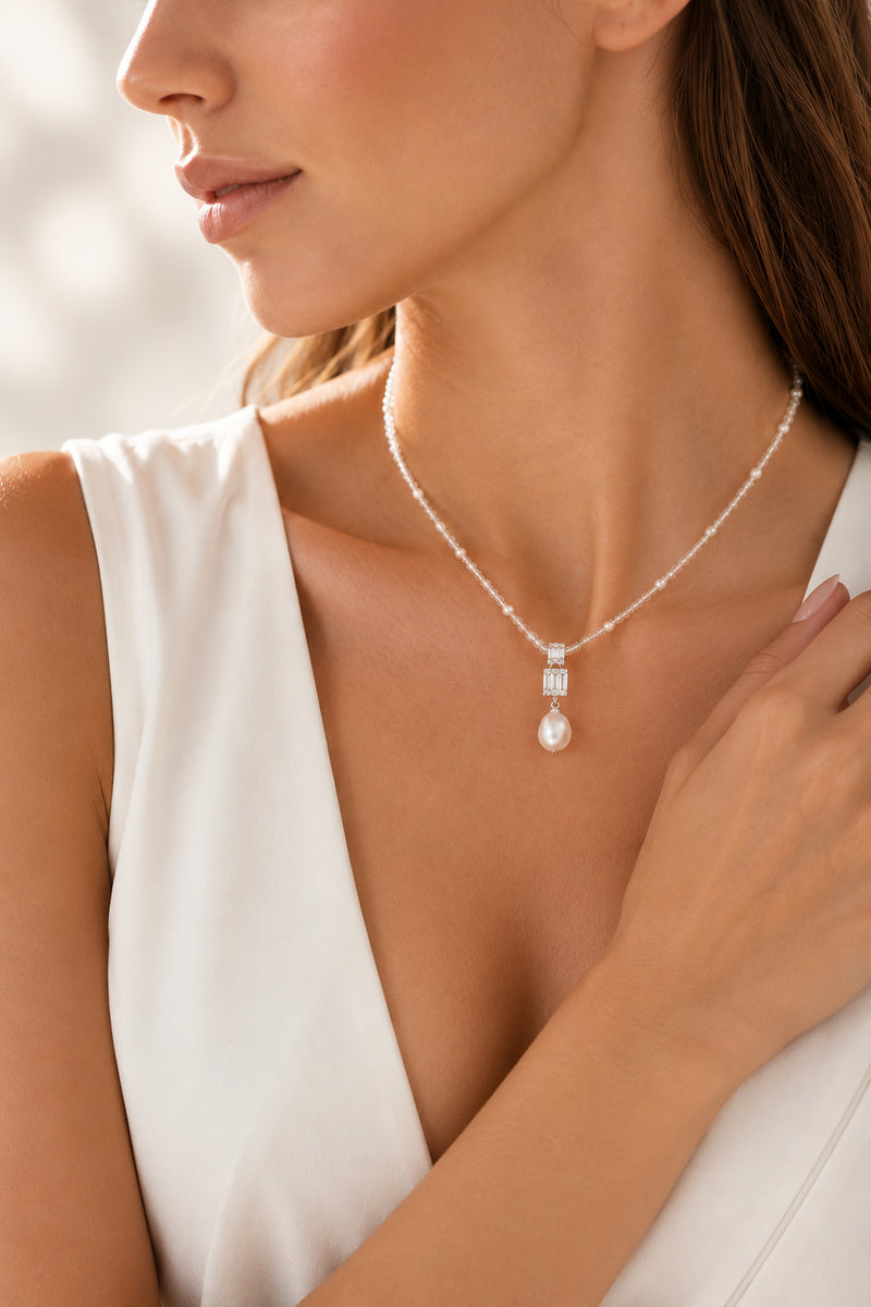 Woman wearing silver-tone necklace with a pear-shaped gemstone drop pendant, VRAEVA