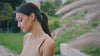 Woman wearing elegant gold hoop earrings and layered necklaces in a natural outdoor setting